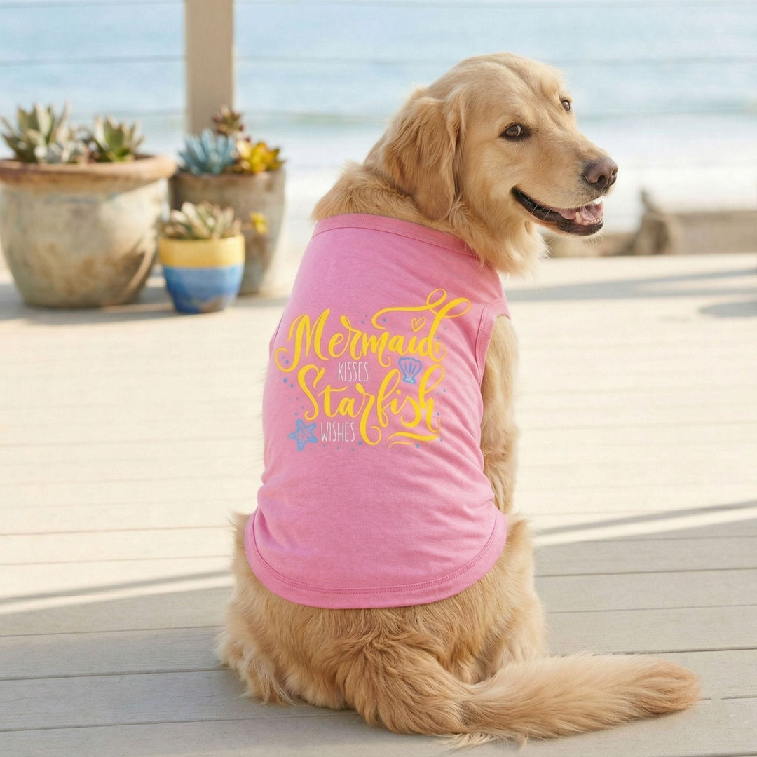 A golden retriever dog  wearing a pink pet shirt with yellow and blue text that reads 'Mermaid with Starfish WISHES'.