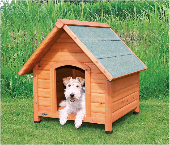 A small dog sits in a wooden dog house with a gray shingled roof. The dog house has a warm honey-toned wood exterior
